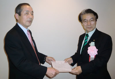 中家校友会会長（左）が山田としお氏に推薦状を手渡す。